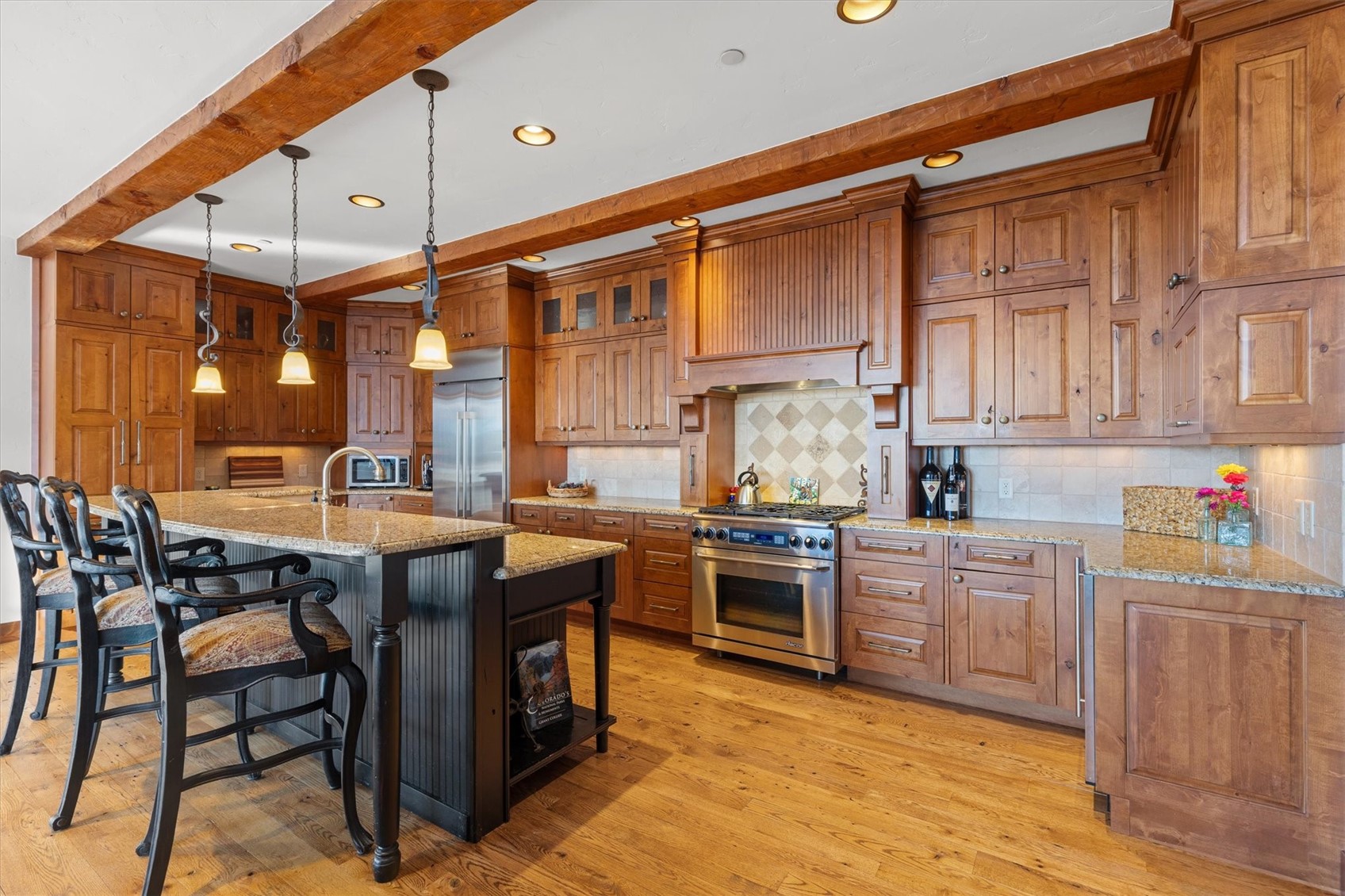 2324 Glacier Ridge, Unit B Steamboat Springs, CO 80487 - Photo 8 of 46 Kitchen featuring brown cabinetry, light stone countertops, beam ceiling, premium appliances, and recessed lighting