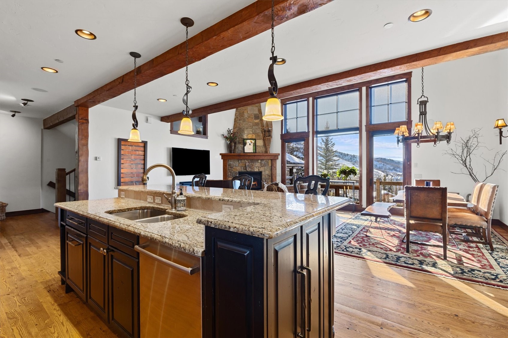 2324 Glacier Ridge, Unit B Steamboat Springs, CO 80487 - Photo 10 of 46 Kitchen with light stone countertops, pendant lighting, a stone fireplace, beam ceiling, and dishwasher