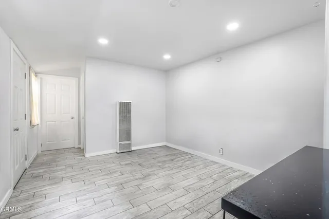 an empty room with wooden floor and bathroom