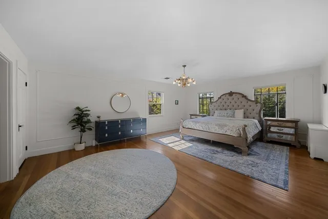 a bedroom with a bed a chandelier and a dresser