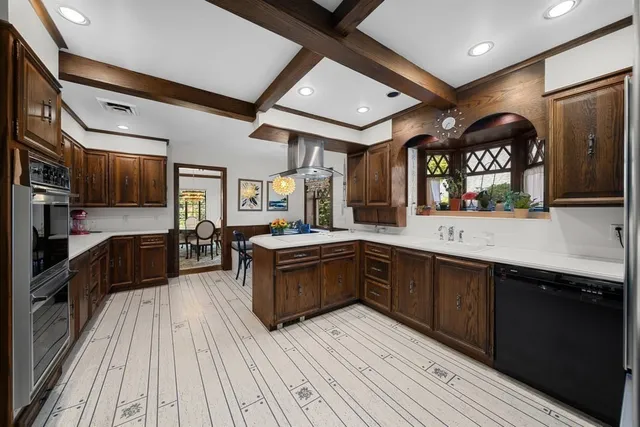 a large kitchen with stainless steel appliances and wooden floor