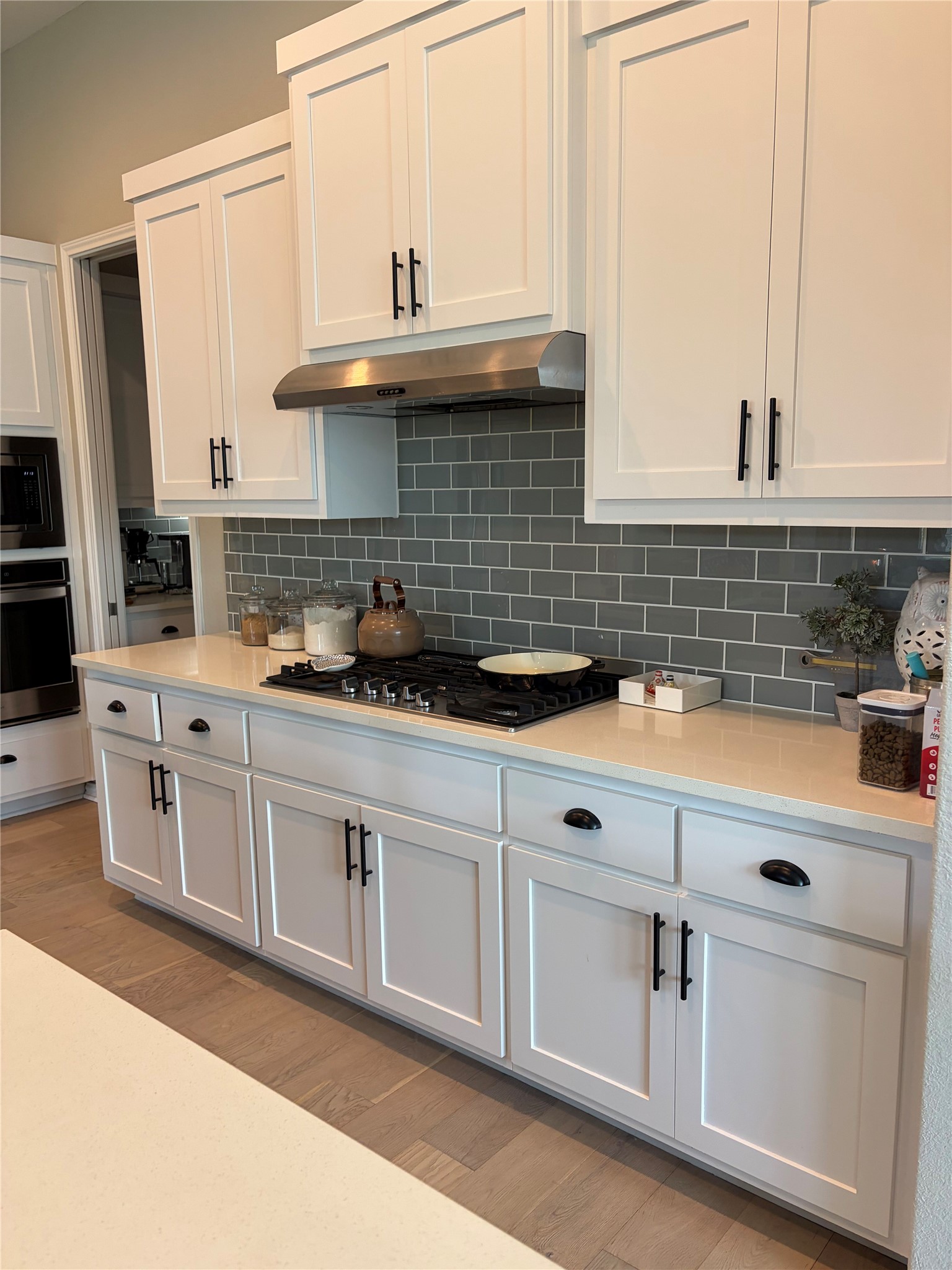 White cabinetry with sleek hardware and quartz countertops create a clean, contemporary kitchen.
