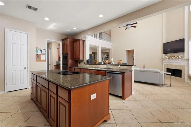 a kitchen with stainless steel appliances granite countertop a stove a sink dishwasher and a flat screen tv