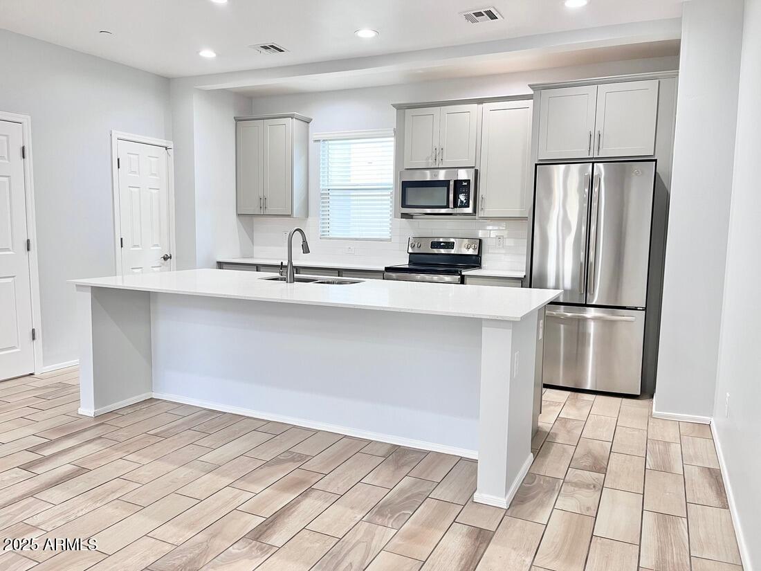 a kitchen with stainless steel appliances a refrigerator sink and microwave