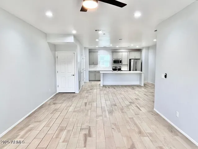 a large kitchen with kitchen island a stove a sink dishwasher a refrigerator and white cabinets with wooden floor