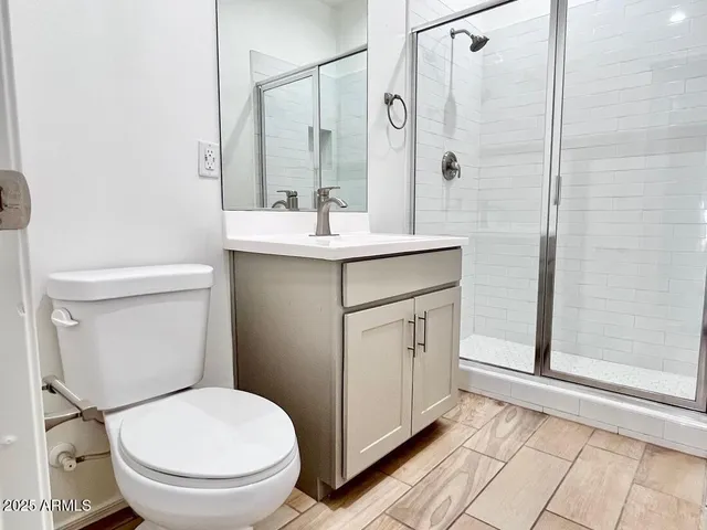 a bathroom with a toilet a sink a mirror and shower
