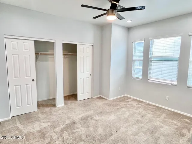 an empty room with a ceiling fan and carpet
