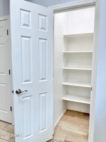 a walk in closet with wooden floor