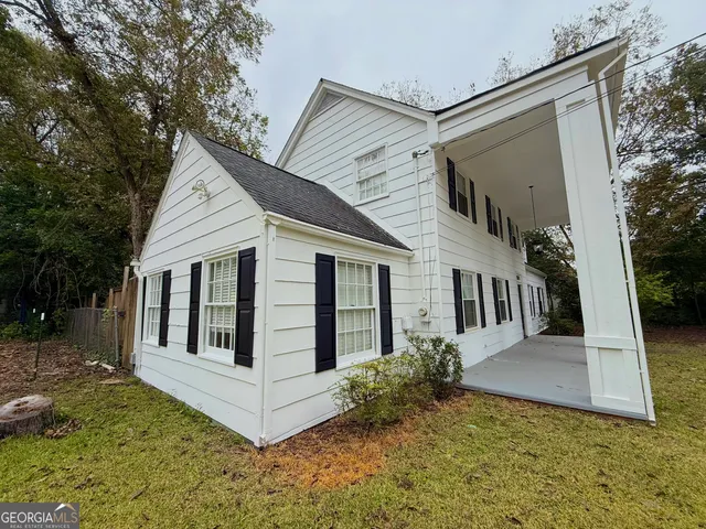 a view of a house with a small yard and large tree