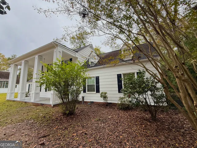 a view of a backyard with plants and large tree