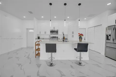 a kitchen with stainless steel appliances kitchen island granite countertop a sink and a refrigerator