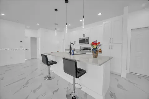 a kitchen with stainless steel appliances kitchen island granite countertop a sink and a refrigerator