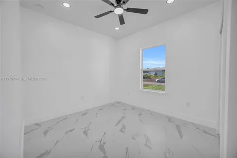 an empty room with chandelier fan and windows
