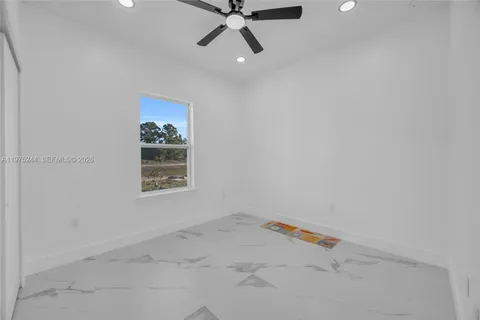 an empty room with a ceiling fan and window
