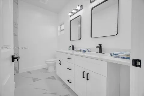 a bathroom with a double vanity sink mirror and toilet