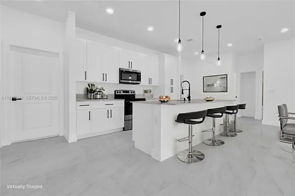 a kitchen with stainless steel appliances a refrigerator a stove a sink a dining table and chairs