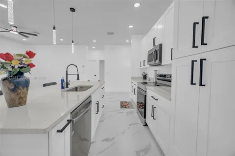 a kitchen with kitchen island white cabinets and refrigerator