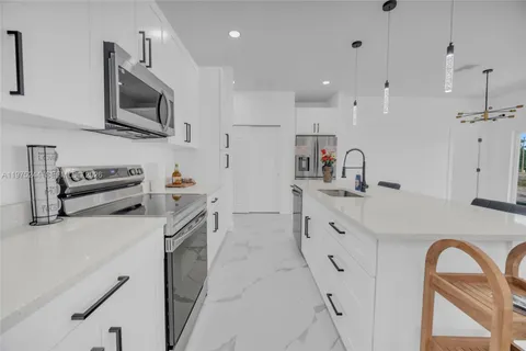 a kitchen with granite countertop a sink stainless steel appliances and white cabinets