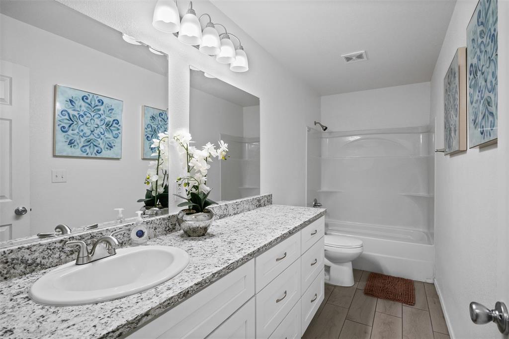 1816 Hidden Valley Road Granbury, TX 76049 - Photo 14 of 23 a bathroom with a granite countertop sink a toilet and shower