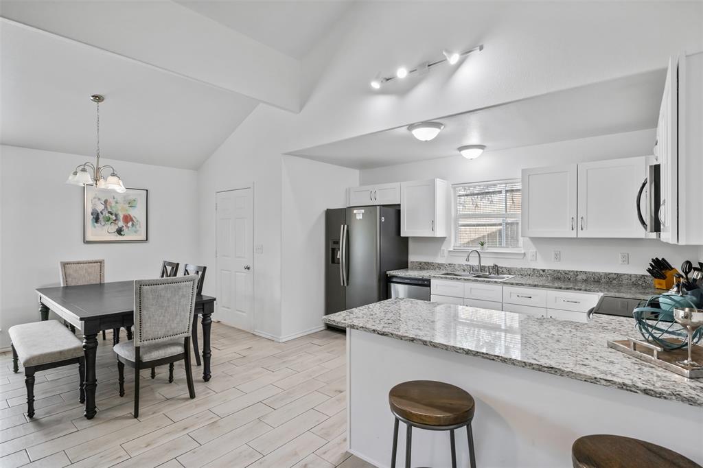 1816 Hidden Valley Road Granbury, TX 76049 - Photo 3 of 23 a kitchen with granite countertop kitchen island a dining table and a refrigerator