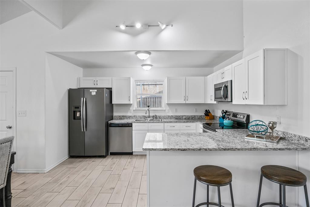1816 Hidden Valley Road Granbury, TX 76049 - Photo 7 of 23 a kitchen with stainless steel appliances granite countertop a refrigerator a sink a stove a dining table and chairs