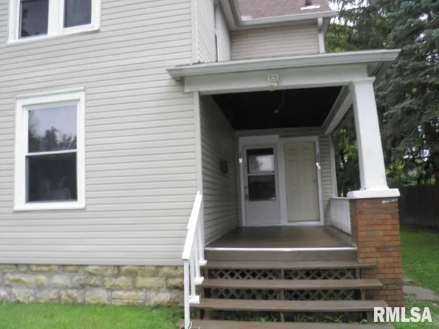 a view of house with entryway and a yard
