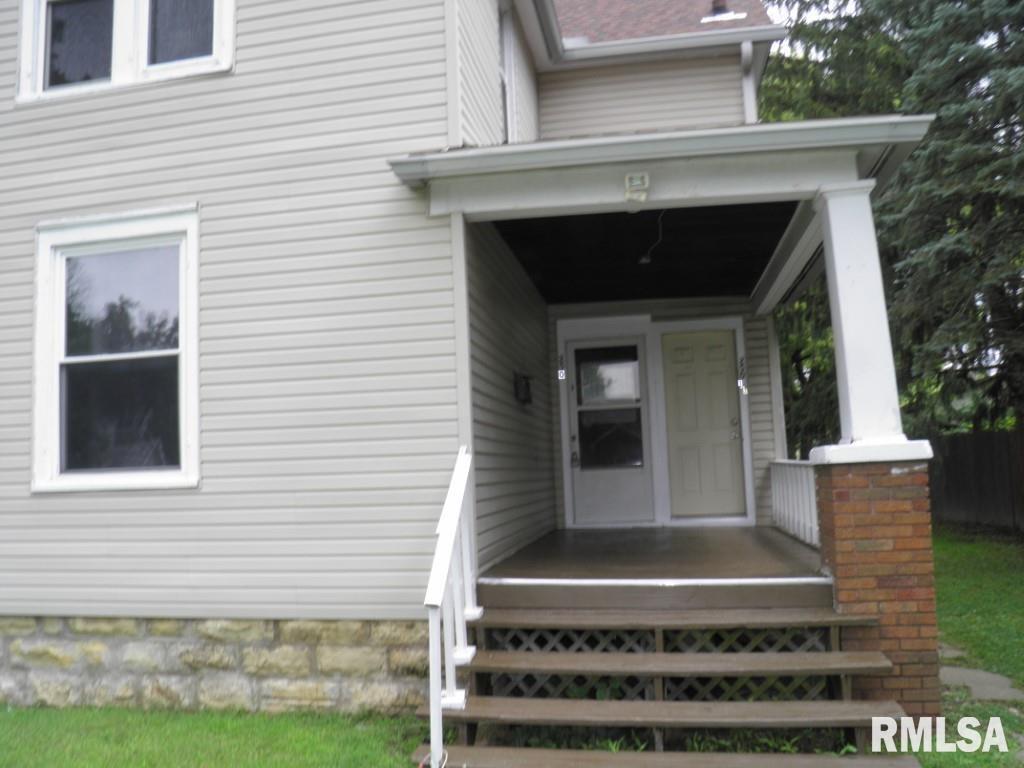 a view of house with entryway and a yard