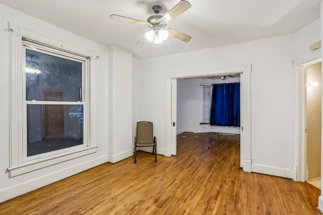 a view of a room with wooden floor and a ceiling fan