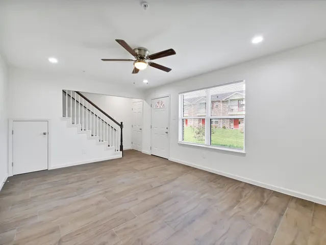a view of an empty room with a window and wooden floor