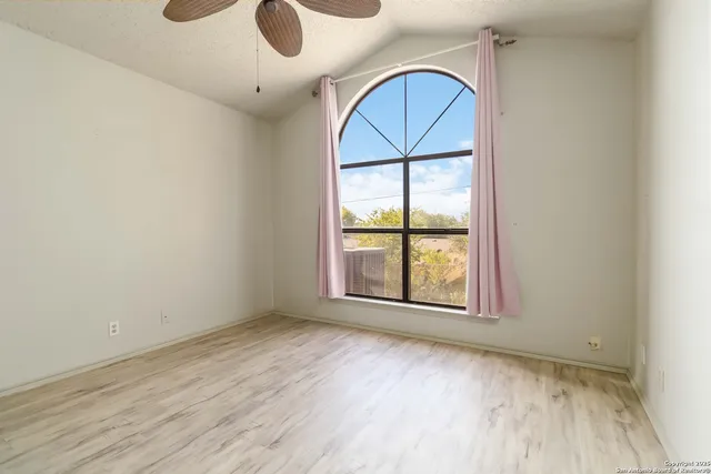 an empty room with wooden floor fan and windows