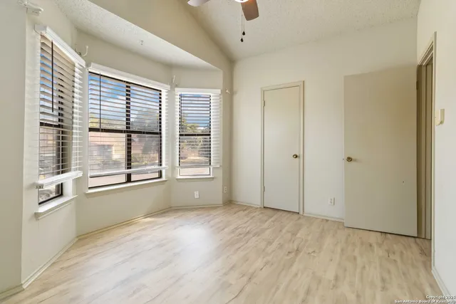 a view of an empty room with a window and wooden floor