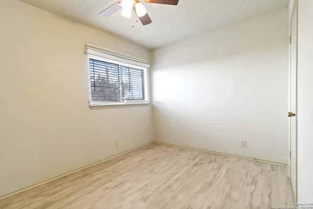 an empty room with a chandelier fan and windows