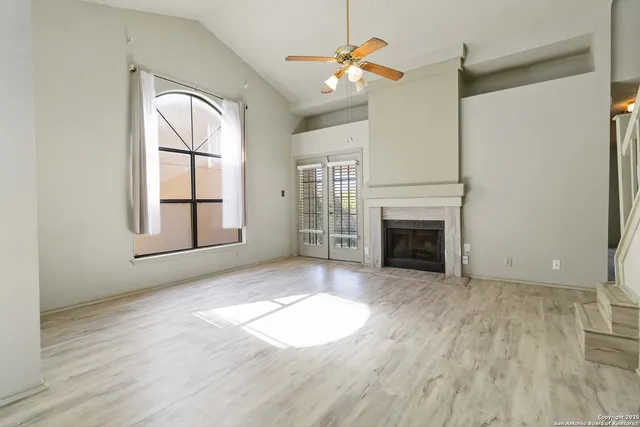 an empty room with windows and fireplace