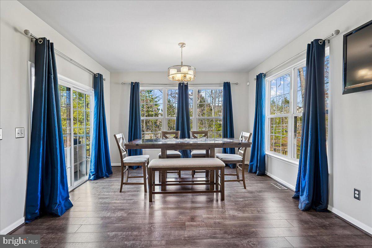 12268 Sedge Street Bristow, VA 20136 - Photo 5 of 48 a dining room with wooden floor a chandelier a glass table and chairs