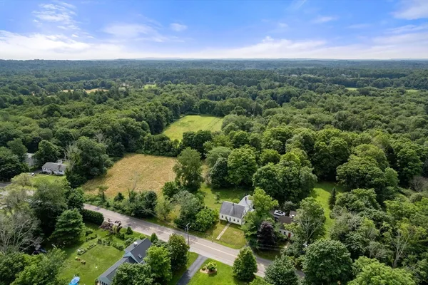 an aerial view of a residential houses with outdoor space and trees