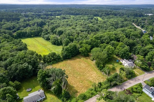 an aerial view of residential house with outdoor space and trees all around