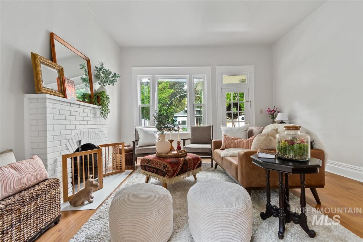 910 North 16th Street Boise, ID 83702 - Photo 7 of 47 Living area featuring a white brick fireplace with an arched opening, wood-finish flooring, and crisp white walls