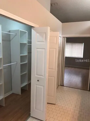 a view of an empty room with wooden floor and a window