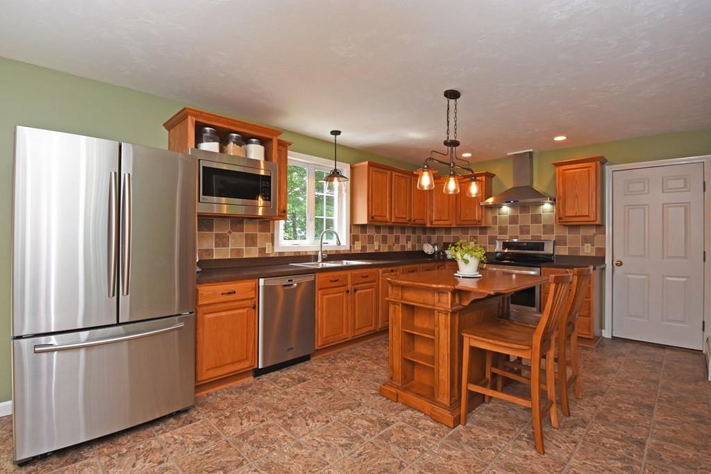 253 Pommogussett Road Rutland, MA 01543 - Photo 2 of 25 a kitchen with stainless steel appliances granite countertop a refrigerator a stove a sink a dining table and chairs with wooden floor