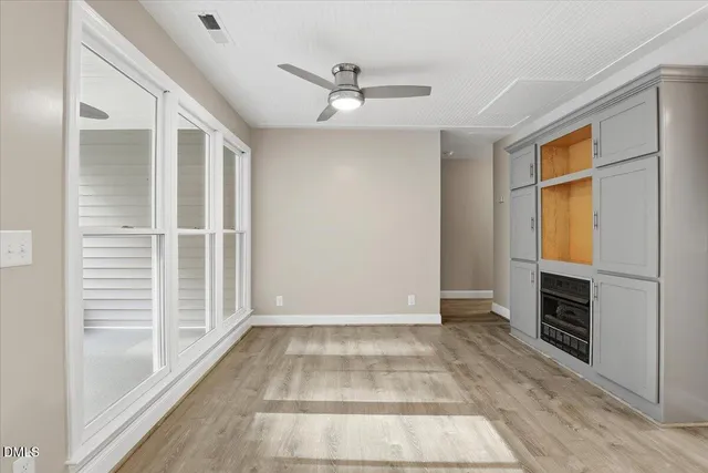 wooden floor in an empty room with a fireplace and a window