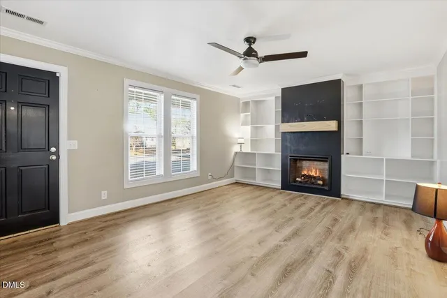 a view of a livingroom with a fireplace a ceiling fan and windows