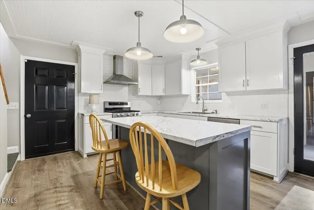 a kitchen with stainless steel appliances granite countertop a stove a refrigerator a sink dishwasher a dining table and chairs with wooden floor