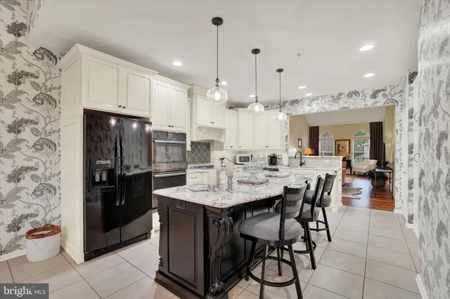 a kitchen with stainless steel appliances kitchen island granite countertop a table chairs sink and cabinets