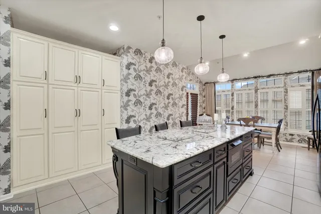 a kitchen with stainless steel appliances kitchen island granite countertop a table chairs and a refrigerator