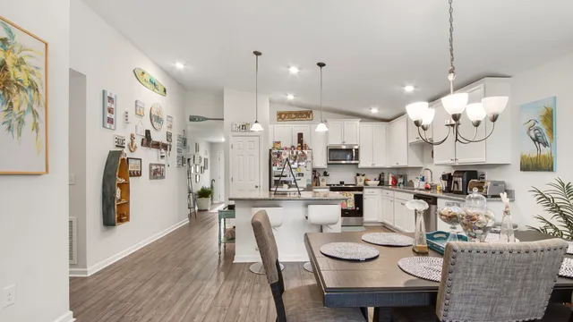 a kitchen with stainless steel appliances kitchen island granite countertop a dining table chairs and a refrigerator