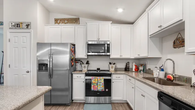 a kitchen with granite countertop a refrigerator and a stove top oven