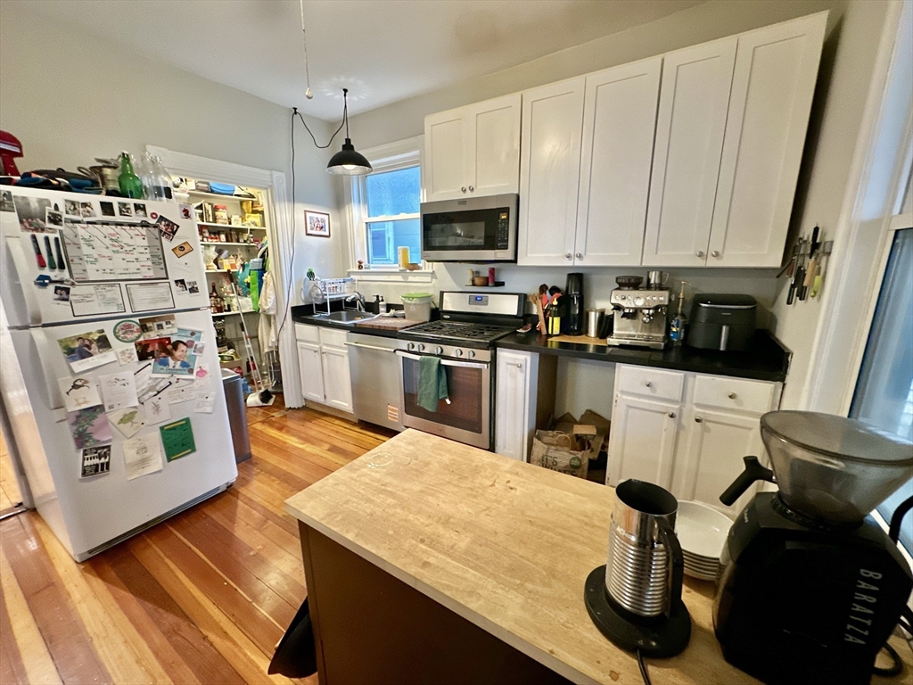 11 Sheridan Street, Unit 2 Boston, MA 02130 - Photo 3 of 17 a kitchen with stainless steel appliances kitchen island granite countertop a sink dishwasher stove and white cabinets
