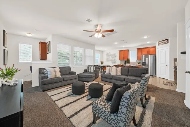 a living room with furniture kitchen view and a chandelier