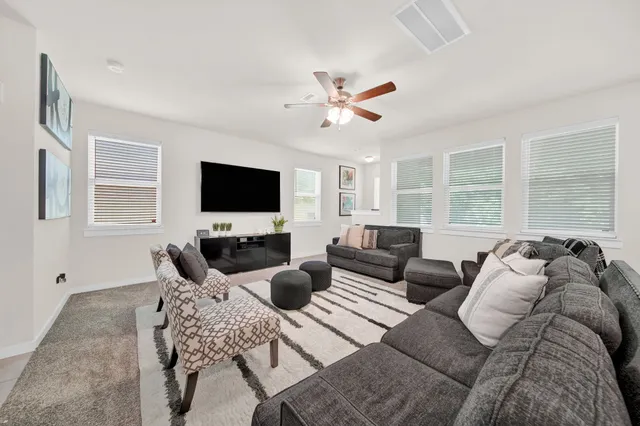 a living room with furniture a flat screen tv and a large window