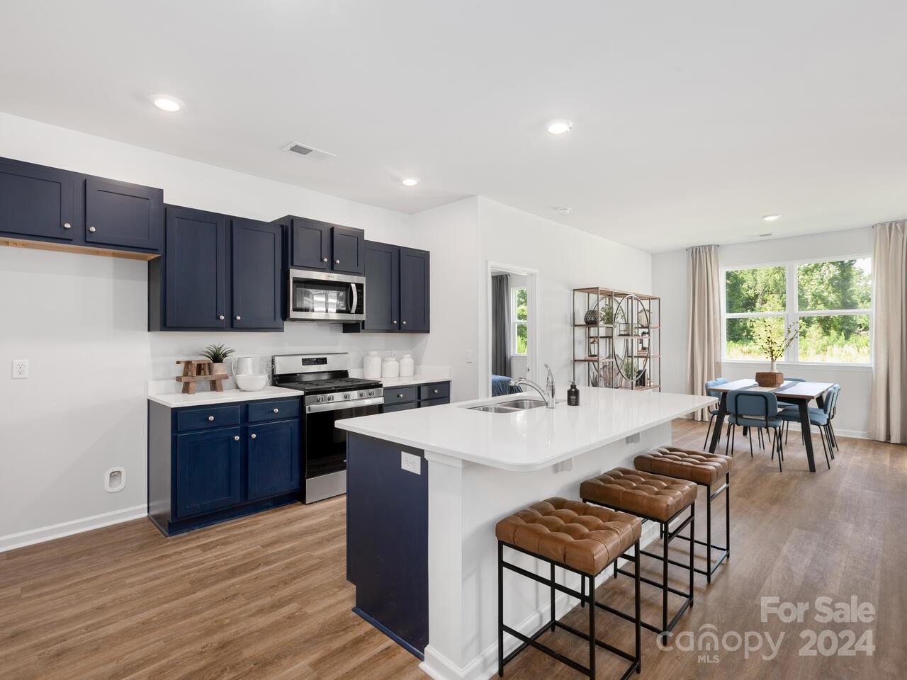 63 Dandelion Road Fletcher, NC 28732 - Photo 5 of 27 a large kitchen with stainless steel appliances granite countertop a stove top oven a sink dishwasher a dining table and chairs with wooden floor
